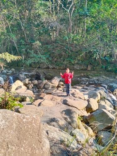 a young boy standing on rocks near a river at 長龍客棧 in Nantou City