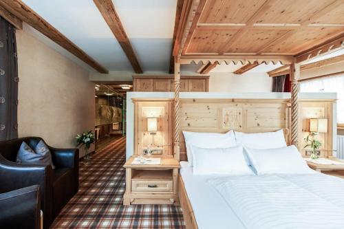 a bedroom with a large bed and a chair at Sport- und Genusshotel Silvretta in Ischgl
