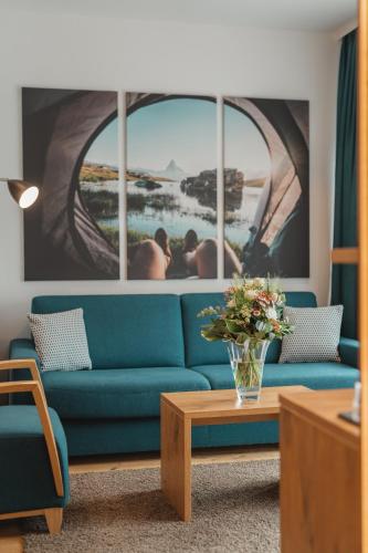 a living room with a blue couch and a window at Alpen Resort & Spa in Zermatt