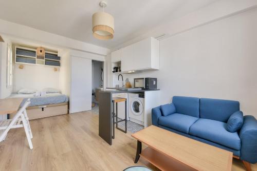 un salon avec un canapé bleu et une cuisine dans l'établissement Splendide studio proche de la station métro Lourmel, à Paris