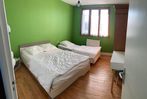 deux lits dans une chambre aux murs verts dans l'établissement maison campagne et mer 10 personnes, à Surville