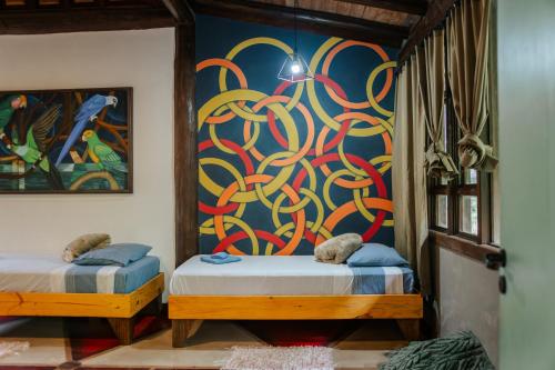 two beds in a room with a painting on the wall at Atelier Arte Paraty Mirim in Paraty