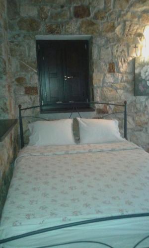 a bedroom with a bed with a stone wall at Yialenia Estate in Rikia