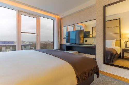 a bedroom with a large bed and a large mirror at Pestana Chelsea Bridge Hotel & SPA in London