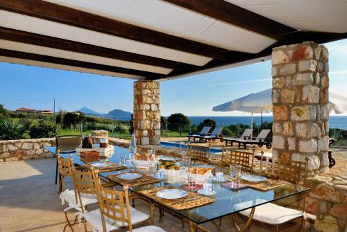 a dining table on a patio with a view of the ocean at Yialenia Estate in Rikia