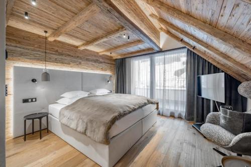 a bedroom with a large bed and wooden ceilings at Sport- und Genusshotel Silvretta in Ischgl