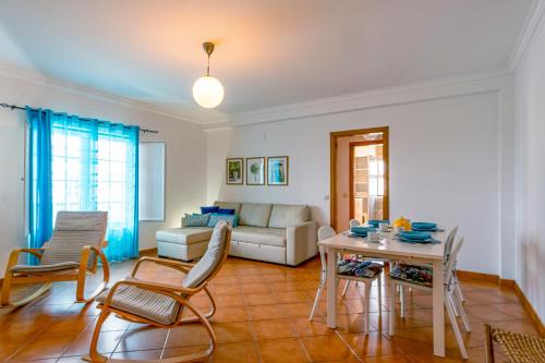 a living room with a table and chairs and a couch at PÉ NA AREIA by Stay in Alentejo in Vila Nova de Milfontes