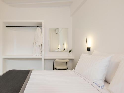 a white bedroom with a white bed and a chair at Sunset Windmills House in Mýkonos City