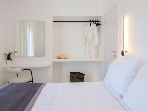 a white bedroom with a bed and a window at Sunset Windmills House in Mýkonos City