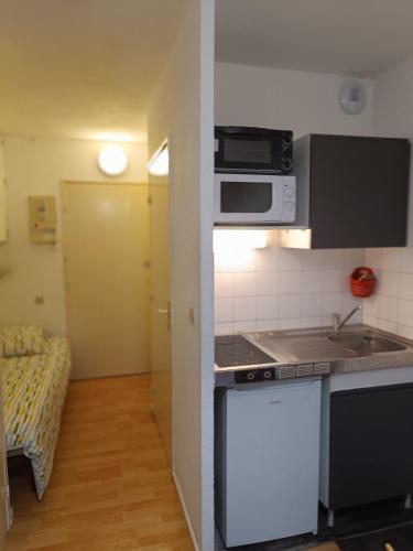 une petite cuisine avec une cuisinière et un micro-ondes dans l'établissement Studio 19m2 rez-de-chaussé, à Lamalou-les-Bains