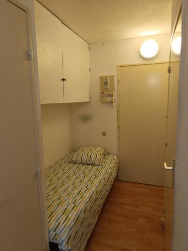 Cette petite chambre comprend un lit et une porte. dans l'établissement Studio 19m2 rez-de-chaussé, à Lamalou-les-Bains