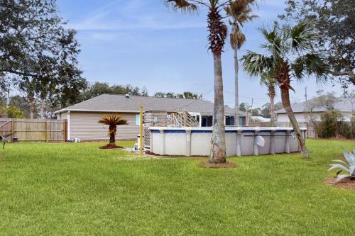 a house with a yard with palm trees and a fence at Poolside Palms Paradise in Navarre