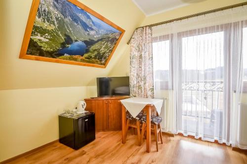 a room with a desk and a table and a window at U Pawlikowskich in Poronin
