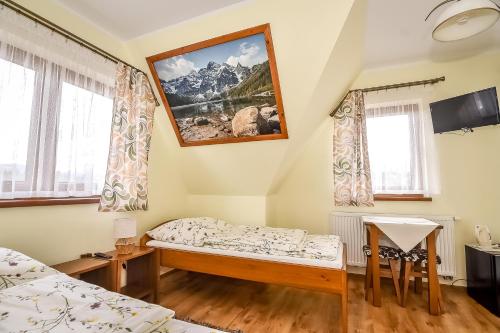 a room with a bed and a tv and two windows at U Pawlikowskich in Poronin