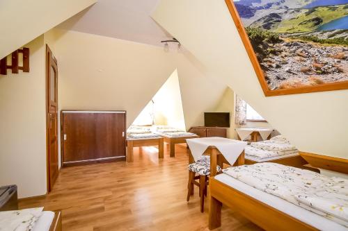 a attic room with beds and a table and chairs at U Pawlikowskich in Poronin