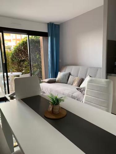 un salon avec un canapé, une table et des chaises dans l'établissement Cosy Blue Classé 2 étoiles Piscine Parking Clim Terrasse, à Cannes