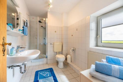 a white bathroom with a sink and a toilet at Ferienhof Bruhn "Nr 3" in Midlum