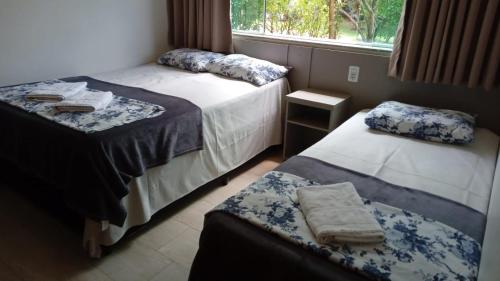 two beds in a room with a window and towels at Pousada Santa Fé in Aparecida