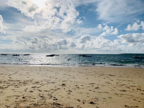 une plage avec des bateaux dans l'eau et des nuages dans l'établissement Pyla sur Mer - Appartement terrasse sous les pins - 200m de la plage, à La Teste-de-Buch
