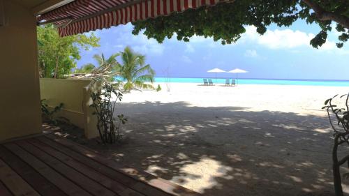 a view of a beach with chairs and umbrellas at Luau Beach Inn, Maldives in Fulidhoo