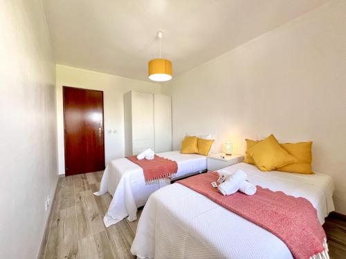 a room with two beds with towels on them at Quarteira Brightness by Homing in Quarteira
