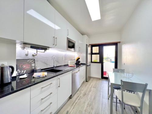 a kitchen with white cabinets and a dining table at Quarteira Brightness by Homing in Quarteira