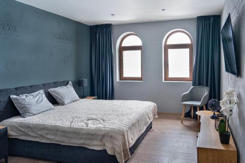 a bedroom with a bed with blue walls and two windows at Калоянова крепост in Arbanasi