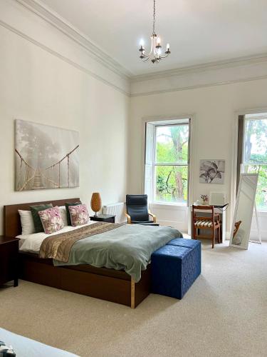 a bedroom with a bed and a chair and windows at Grosvenor Apartments in Bath - Great for Families, Groups, Couples, 80 sq m, Parking in Bath