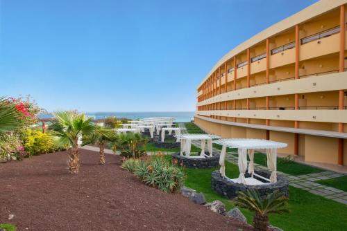 a building with a table and palm trees in front of it at Iberostar Waves Playa Gaviotas All Inclusive in Morro del Jable