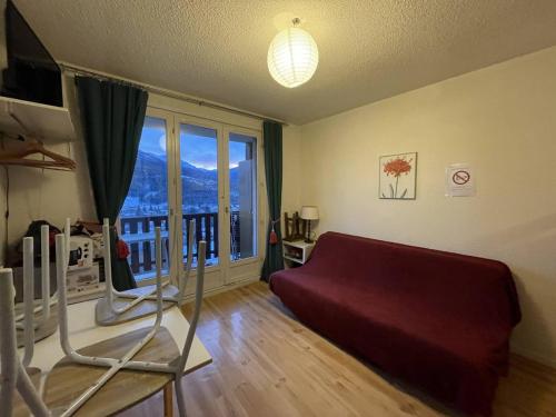 un salon avec un canapé et une grande fenêtre dans l'établissement Charmant T2 à Barcelonnette avec balcon et parking - FR-1-804-43, à Barcelonnette