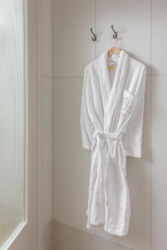 a white robe hanging on a rack in a bathroom at Hotel Carmel  in Haifa
