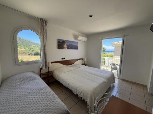 une chambre avec deux lits et une grande fenêtre dans l'établissement Les Villas Maristella, Villa Crenu, à Aregno