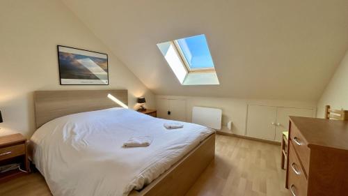 une chambre avec un grand lit blanc avec deux puits de lumière dans l'établissement Tribord, charmante maison en duplex au cœur du Crotoy – Idéale pour un séjour en Baie de Somme, au Crotoy