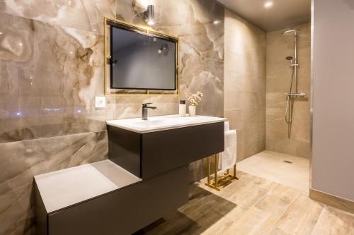 a bathroom with a sink and a television on the wall at Suite & Spa Le Clandestin ARRAS in Arras