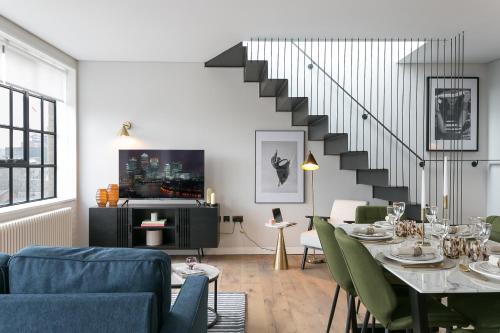 a living room with a table and a staircase at Urban Chic - Clink Street in London