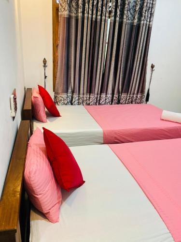 two beds in a room with red and white pillows at The Green Garden in Dambulla