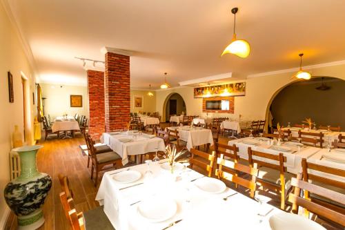 a restaurant with white tables and chairs and a brick wall at Continent Hotel Kapadokus Thermal in Guzelyurt