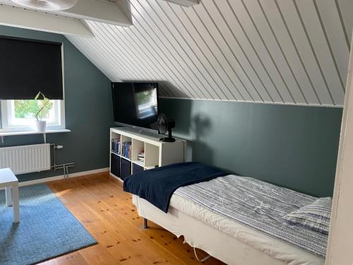 a bedroom with a bed and a tv in a attic at Family-friendly house near the sea in TrÃ¤slÃ¶vslÃ¤ge
