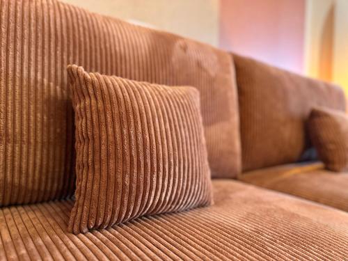 a brown couch with two pillows on it at Le Terrazzo - Élégant - Centre - Balcon - Lumineux in Mont-de-Marsan