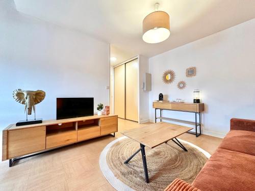 a living room with a couch and a flat screen tv at Le Terrazzo - Élégant - Centre - Balcon - Lumineux in Mont-de-Marsan