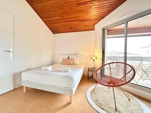 a bedroom with a bed and a chair and a window at Le Terrazzo - Élégant - Centre - Balcon - Lumineux in Mont-de-Marsan