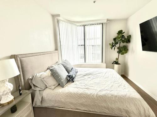 a white bedroom with a bed with pillows and a window at Spacious and Central with a Pool View in Los Angeles