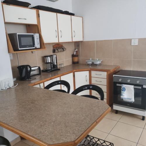 a kitchen with white cabinets and a table with chairs at Michelle's Cottage by the Sea in Port Shepstone