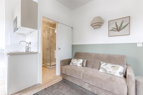 un salon avec un canapé et une cuisine dans l'établissement Mykeypers - Studio Deluxe 2P - Malakoff 16, à Malakoff