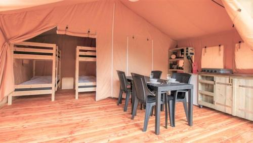 a dining room with a table and chairs in a tent at Safaritenten Schotererf in Kuinre