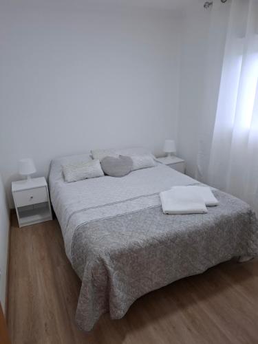 a white bedroom with a bed with two towels on it at Casinha Branca in Horta