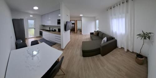a living room with a couch and a table and a kitchen at Casinha Branca in Horta