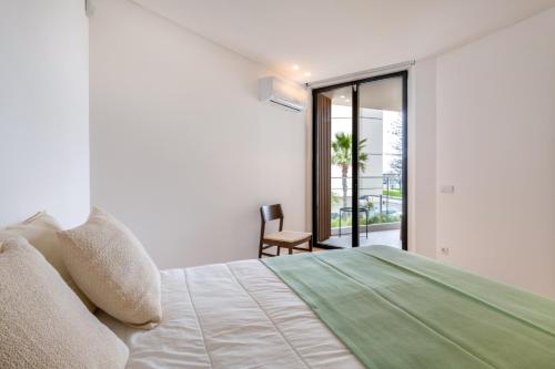 a white bedroom with a bed and a balcony at Del Marina Apartment in Olhão