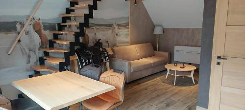 a living room with a staircase with a couch and a table at Gite équestre - Domaine aux charmes d'Ethan in Hannut