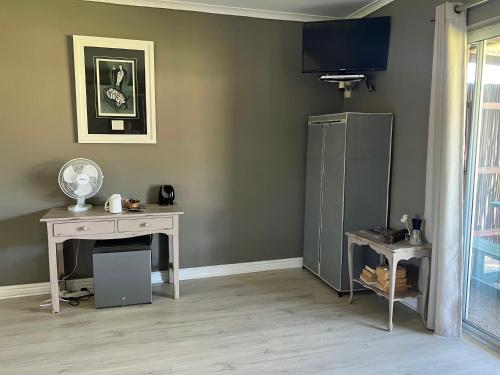 a room with a desk and a television on a wall at Tenikwa Wildlife Centre & Spa in Plettenberg Bay